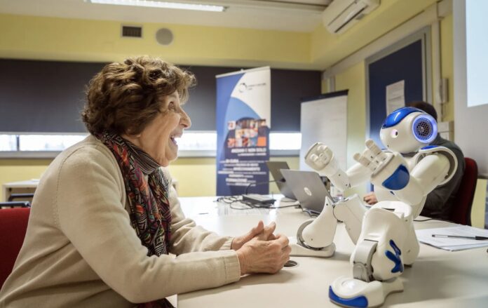 Bona Poli, de 85 años, le pide al robot Nao que le cuente un cuento durante un grupo de discusión en Carpi, Italia - Alessandro Grassani